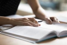 Person's hand on an open textbook.
